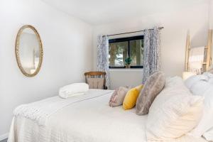 ein Schlafzimmer mit einem weißen Bett mit Kissen und einem Spiegel in der Unterkunft Scenic - Holiday Haven - 4 Minutes to Beaver Creek in Avon