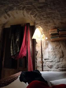1 dormitorio con 1 cama y una lámpara en una pared de piedra en CASA Adriana Affascinante casa in pietra, en Buseto Palizzolo