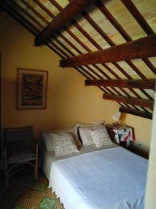 een slaapkamer met een wit bed en een stoel bij CASA Adriana Affascinante casa in pietra in Buseto Palizzolo