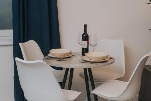 een tafel met witte stoelen en een fles wijn bij Apartman Godot in Zagreb +23 foto's