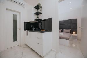 een witte keuken met een wastafel en een bed bij Apartman Godot in Zagreb