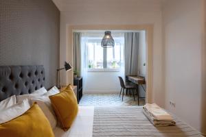 ein Schlafzimmer mit einem Bett mit gelben Kissen und einem Schreibtisch in der Unterkunft DuMont Lisbon Guesthouse in Lissabon