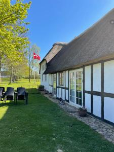 欧登塞Baekgaarden 3 rooms Apartment - old farm house的白色和黑色的建筑,配有椅子和旗帜