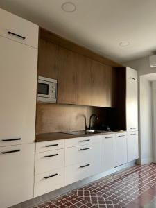 eine Küche mit weißen Schränken und einer Mikrowelle in der Unterkunft CÉNTRICO APARTAMENTO REFORMADO EN ARANJUEZ in Aranjuez