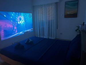 1 dormitorio con cama azul y ventana grande en 一线海景房seaview apartment, en Artemida