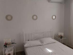 1 dormitorio con 1 cama blanca y 2 relojes en la pared en Apartment Matovic en Tesalónica