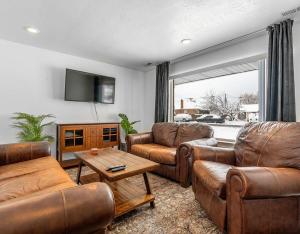 a living room with leather furniture and a flat screen tv at Modern home near UVU and BYU with hot tub and mountain views in Orem