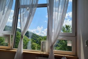 a window with white curtains and a view of a waterfall at Rabarbar in Ustroń