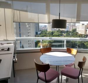 a kitchen with a table and chairs in front of a window at Apartamentos Juliana Bela Vista in Sao Paulo