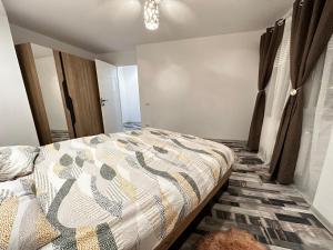 a bedroom with a bed with a comforter on it at Emm’a in Ploieşti