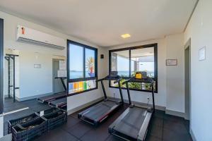 un gimnasio con dos cintas de correr y dos ventanas en Aion Suítes - Exclusivo Loft, Praia de Bombinhas, en Bombinhas