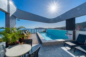 balcón con piscina, mesa y sillas en Aion Suítes - Exclusivo Loft, Praia de Bombinhas, en Bombinhas