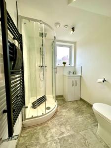 a bathroom with a shower and a toilet and a sink at Large New 4 bedroom House Sleeps up to 12 - Accepts Groups - Great Location - FREE Parking - Fast WiFi - Smart TVs - sleeps up to 12 people - Close to Bournemouth & Poole Town Centre & Sandbanks in Bournemouth