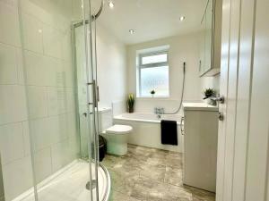 a bathroom with a shower and a toilet and a sink at Large New 4 bedroom House Sleeps up to 12 - Accepts Groups - Great Location - FREE Parking - Fast WiFi - Smart TVs - sleeps up to 12 people - Close to Bournemouth & Poole Town Centre & Sandbanks in Bournemouth