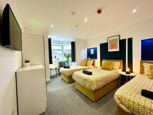 a hotel room with two beds and a flat screen tv at Large New 4 bedroom House Sleeps up to 12 - Accepts Groups - Great Location - FREE Parking - Fast WiFi - Smart TVs - sleeps up to 12 people - Close to Bournemouth & Poole Town Centre & Sandbanks in Bournemouth
