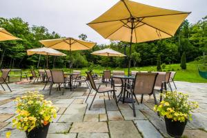 un patio con mesas, sillas y sombrillas en Skihaven East Glade A1, en Killington