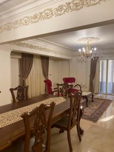 comedor con mesa, sillas y lámpara de araña en Luxurious, fully furnished and well-equipped apartment with modern amenities, stunning views, and convenient location for remote work or studying from home, en El Cairo