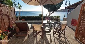 a patio with a table and chairs and an umbrella at ANEMOESSA APTS in Livadia