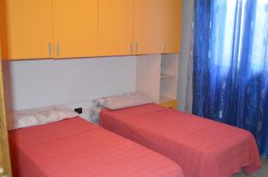 dwa łóżka w pokoju z pomarańczowymi szafkami w obiekcie Casa vacanze da Anna w mieście Tortolì