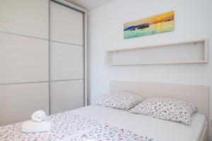 a white bedroom with a bed and pillows at VDL Apartments in Trogir