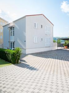 a white house with a brick driveway in front of it at VDL Apartments in Trogir