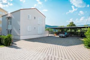 a white house with a car parked in a driveway at VDL Apartments in Trogir