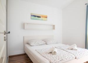 a white bedroom with a bed with two pillows at VDL Apartments in Trogir