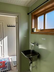 La salle de bains est pourvue d'un lavabo et d'une fenêtre. dans l'établissement Olenilsøy Cabins, à Reine