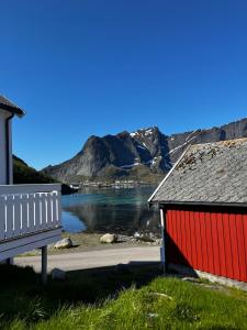 a red building with a bench next to a body of water at Anitas Waterfront Cabins in Reine