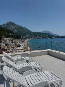 een rij witte ligstoelen op een balkon met uitzicht op het water bij Hotel Kaligrosh in Sutomore
