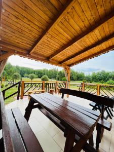 - une table de pique-nique en bois sur une terrasse couverte avec un toit dans l'établissement Dom nad stawem, à Żywki