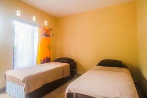 2 łóżka w pokoju z żółtymi ścianami i oknem w obiekcie Hotel Cemerlang w mieście Baturaden