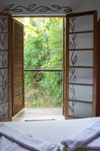 a bedroom with a window looking out at a garden at Sambaqui Hostel in Ilhabela