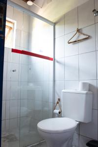 a bathroom with a toilet and a glass shower at Sambaqui Hostel in Ilhabela