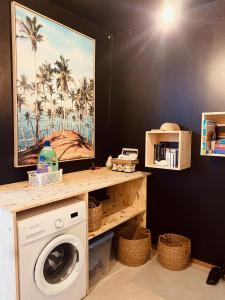 a laundry room with a washing machine and a picture of palm trees at ZANNANNA LODGE in Le Diamant