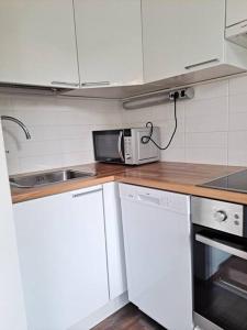 a kitchen with white cabinets and a sink and a microwave at Puotilan idylli meren lähellä in Helsinki