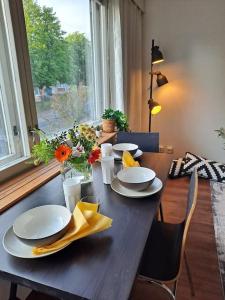 una mesa de madera con platos y flores. en Puotilan idylli meren lähellä en Helsinki