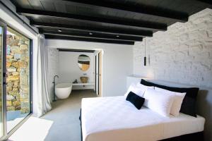 una camera con letto bianco e vasca da bagno di Blue Eye Grand Villa Mykonos a Kalafatis