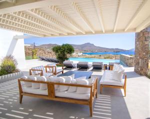 une terrasse avec une table, des chaises et une piscine dans l'établissement Blue Eye Grand Villa Mykonos, à Kalafatis