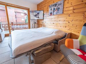 a bed in a room with a wooden wall at Appartement Huez, 2 pièces, 5 personnes - FR-1-645-17 in LʼHuez