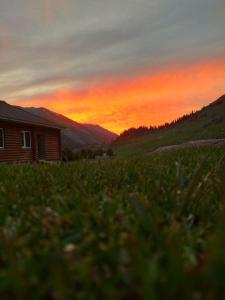 a house in a field with a sunset in the background at Altyn Arashan guesthouse in Mineralʼnyy Istochnik Altyn-Arasan