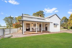 a white house with a deck and a yard at The Bank House Ulmarra in Ulmarra