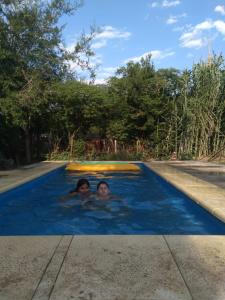 Dos personas están nadando en una piscina en El rancho de mi abuelo en San Antonio de Areco