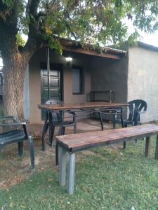una mesa de picnic y bancos sentados bajo un árbol en El rancho de mi abuelo en San Antonio de Areco