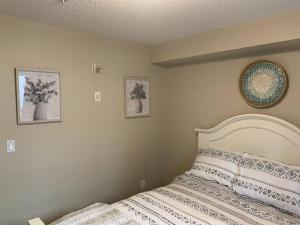 - une chambre avec un lit et deux photos sur le mur dans l'établissement Chris's Cozy Condo Times Square Rogers Place Edmonton, à Edmonton