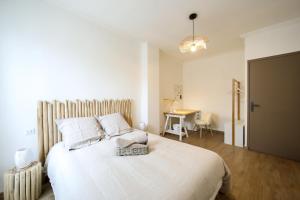 1 dormitorio con 1 cama blanca grande y escritorio en Le lavandin, spacieux et moderne P4, centre ville, wifi, en Nimes
