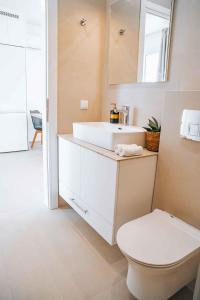 een badkamer met een witte wastafel en een toilet bij Grand White Apartments in Agios Ioannis
