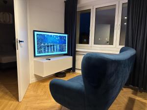 a living room with a blue chair and a television at Mały Kwadrat Katowice in Katowice