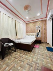 a bedroom with a bed and a chair and a television at The Bella Guesthouse in Varanasi
