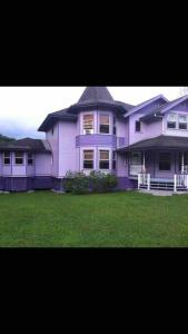 a large purple house with a green yard at Hawaii Tropical Volcano mansion + Sauna in Hilo